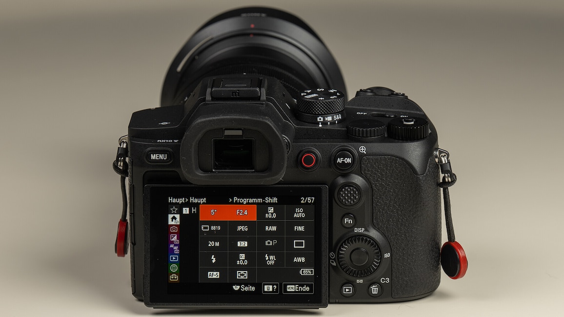 Rückansicht der Sony Cyber-shot RX10 V auf einem weißen Tisch. Auf dem Display ist das Kameramenü zu sehen.