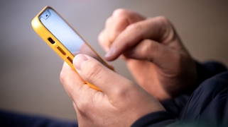 Mann tippt auf einem Smartphone in gelber Hülle