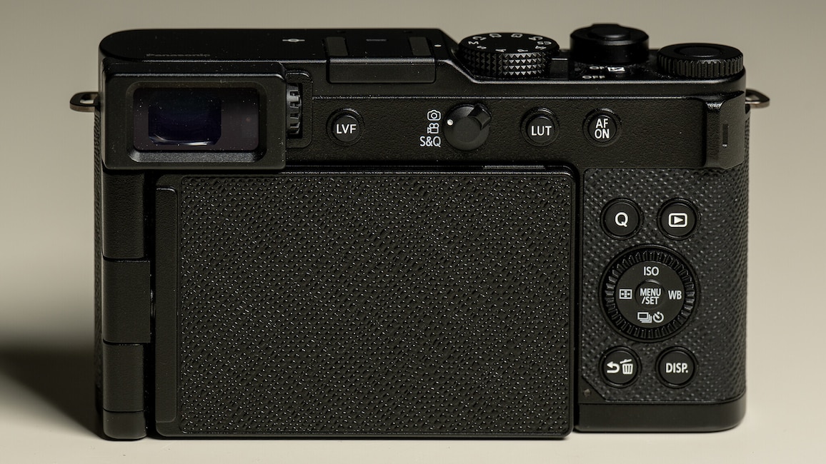 Ansicht der Rückseite der Panasonic Lumix L10 mit eingeklapptem Display. Die Kamera steht auf einem weißen Tisch.