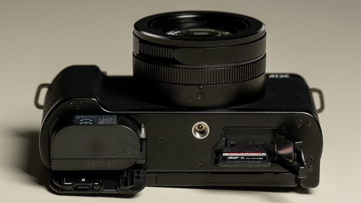 Ansicht der Unterseite der Panasonic Lumix L10. Die Kamera liegt auf einem weißen Tisch.