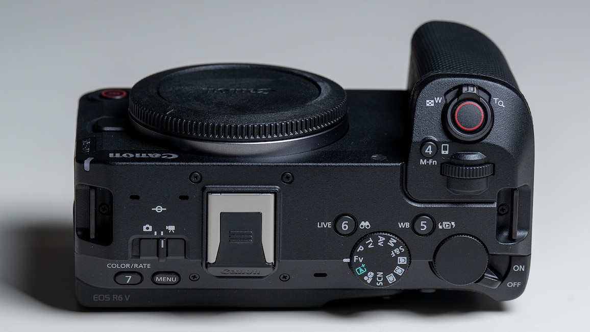 Ansicht des Gehäuses der Canon EOS R6 V von oben. Die Kamera liegt auf der Rückseite auf einem weißen Tisch.