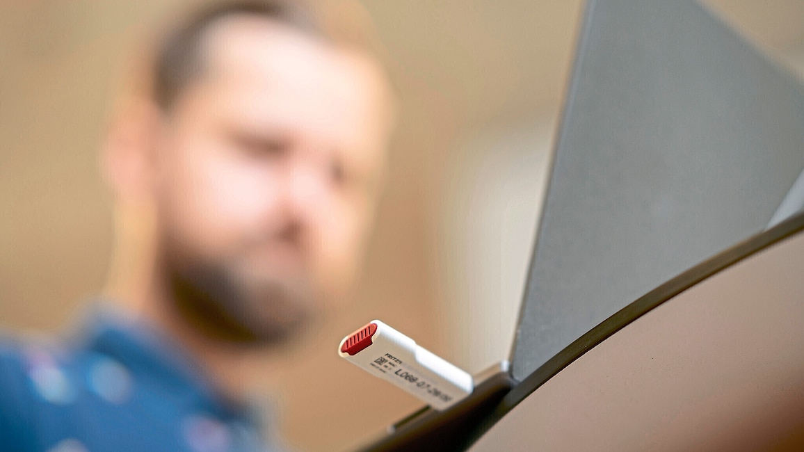 FritzWLAN Stick 6700 am Laptop eingesteckt mit männlicher Person unscharf im Hintergrund
