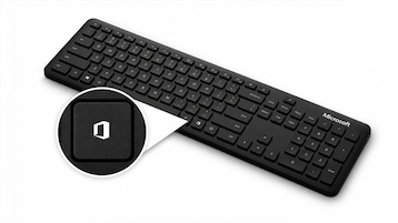 Schwarze Microsoft-Tastatur vor hellem Hintergrund. Eine vergrößerte Darstellung hebt eine Taste mit dem Microsoft-Office-Logo hervor. Die Tastatur enthält einen Nummernblock sowie Standardtasten, rechts ist der Schriftzug „Microsoft“ zu sehen. Die hervorgehobene Taste befindet sich im unteren linken Bereich der Tastatur.