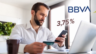Ein Mann am Schreibtisch mit Smartphone und Bankkarte in den Händen; das BBVA-Logo und 3,75 Prozent eingeblendet