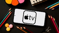 Logo von Apple TV auf einem Smartphone, das auf einem Tisch liegt.
