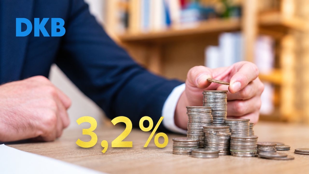 Eine Person legt eine Münze auf einen Münzstapel. Daneben stehen weitere Münzstapel auf einem Tisch. Links oben ist das DKB-Logo zu sehen, unten steht „3,2%“. Im Hintergrund sind unscharfe Regale zu erkennen.