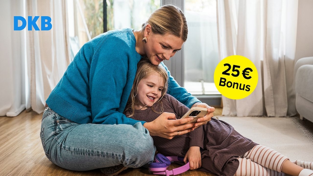 Eine Frau sitzt mit einem Kind auf dem Boden und hält ein Smartphone in der Hand. Links oben steht das DKB-Logo, rechts ist ein gelber Kreis mit der Aufschrift „25 € Bonus“ eingeblendet. Im Hintergrund sind Fenster, Vorhänge und ein Sofa zu sehen.