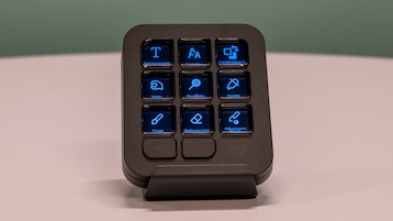 Das Logitech MX Keypad steht auf einem weißen Tisch vor einem grünen Hintergrund.