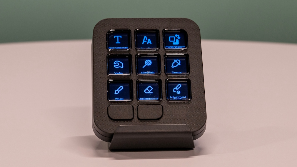 Das Logitech MX Keypad steht auf einem weißen Tisch vor einem grünen Hintergrund.
