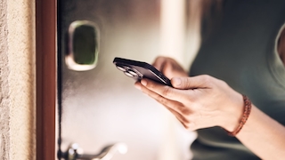 Frau hält iPhone an Haustür