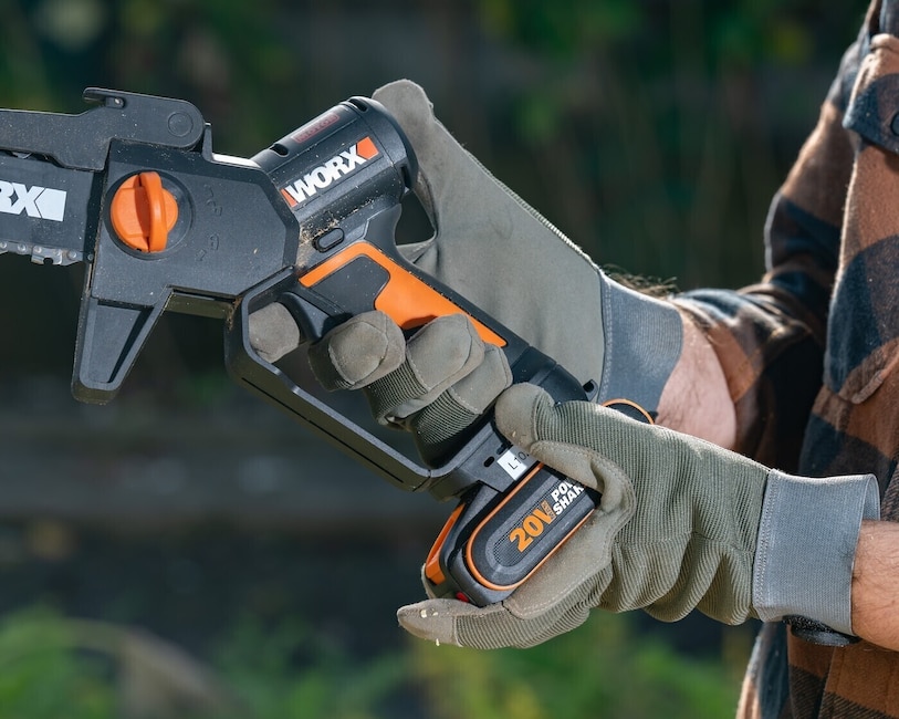Zwei behandschuhte Hände halten die Worx-Säge.