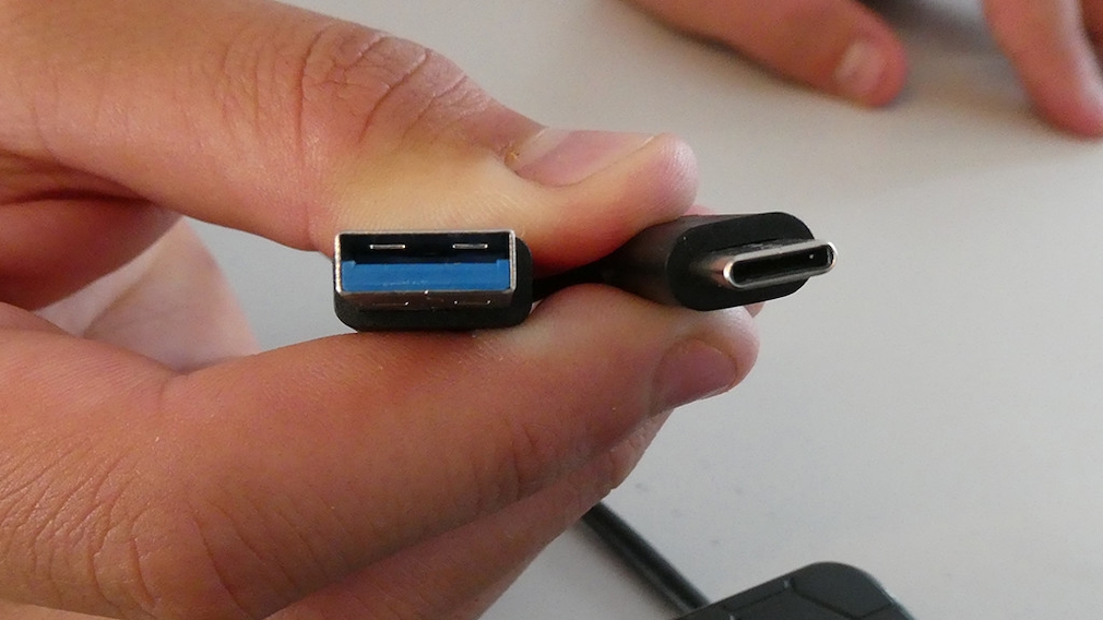 Hand holds USB type A and USB-C plugs
