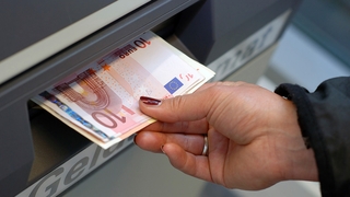 Hand zieht Geld aus Geldautomaten
